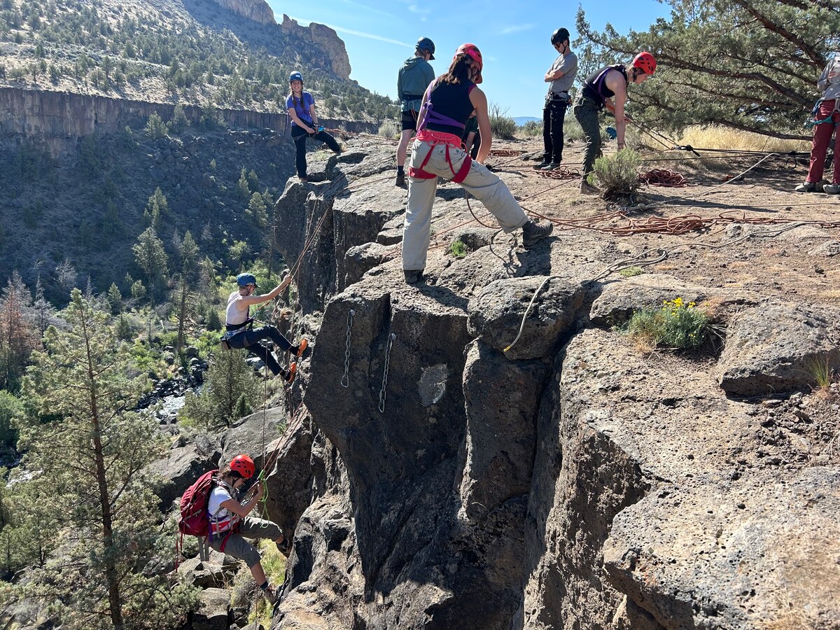 Students practice climbing and rappelling in a rocky canyon.