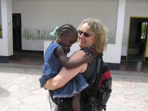 A woman wearing a backpack and carrying a young boy