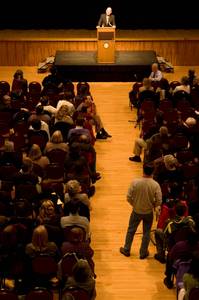A man speaks at a podium in front of a crowd