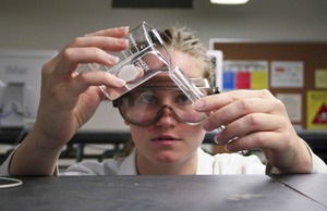 A young woman pours liquid from a beaker to a test tube