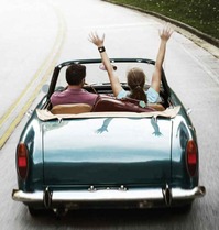 A man and a woman drive down a road