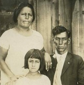 A girl and her parents outside their house