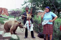 A woman, a man playing an instrument, and a bear on a leash