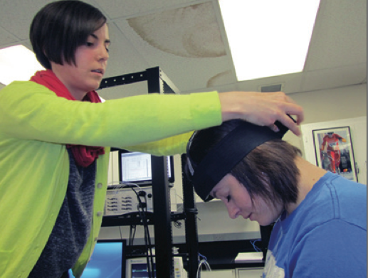 A woman places a brain cap on a young girl