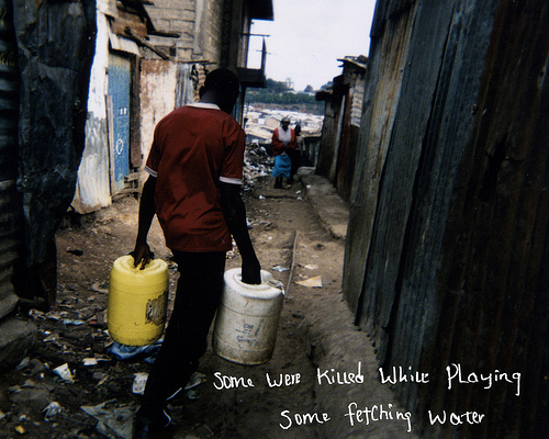 A man carrying buckets through slums