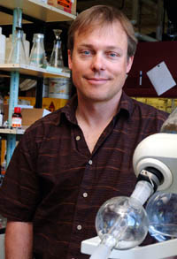 A man in front of shelves of glass bottles in a laboratory