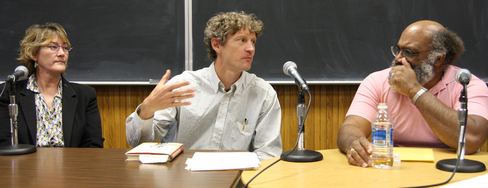 A panel of three professors talking into microphones at a table