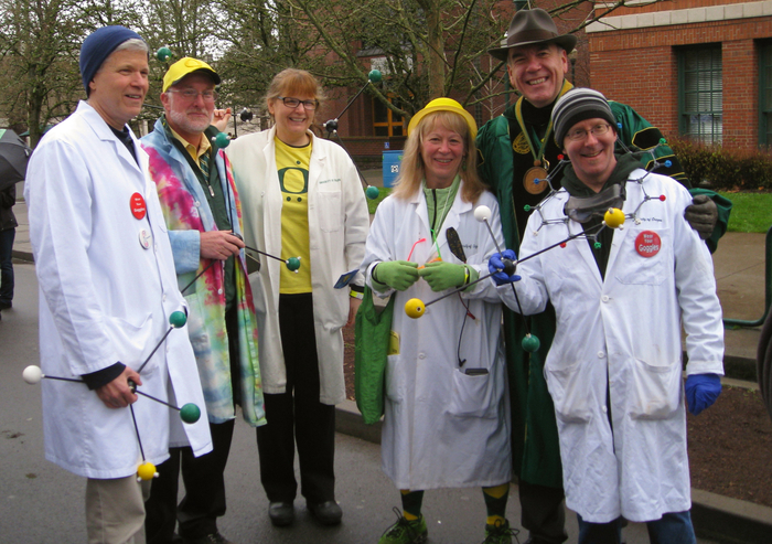 Men and women pose in lab coats and graduation gear