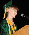A woman wearing a cap and gown, standing at a podium