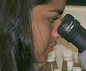 A young woman looking into a microscope