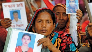 Female factory workers hold up photos of lost loved ones