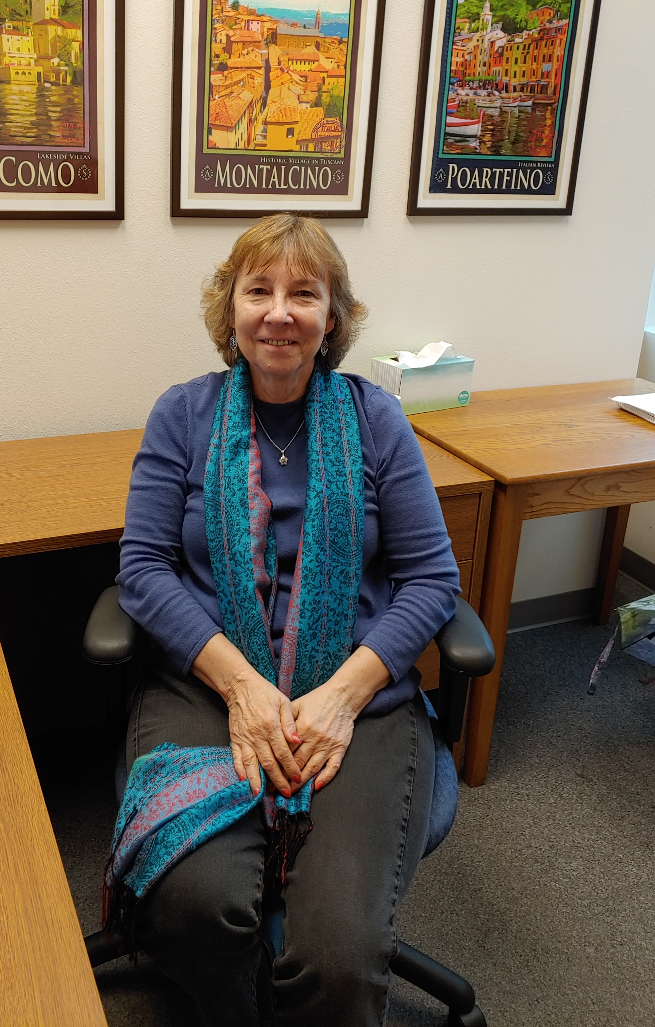 woman sitting in chair with travel posters behind her