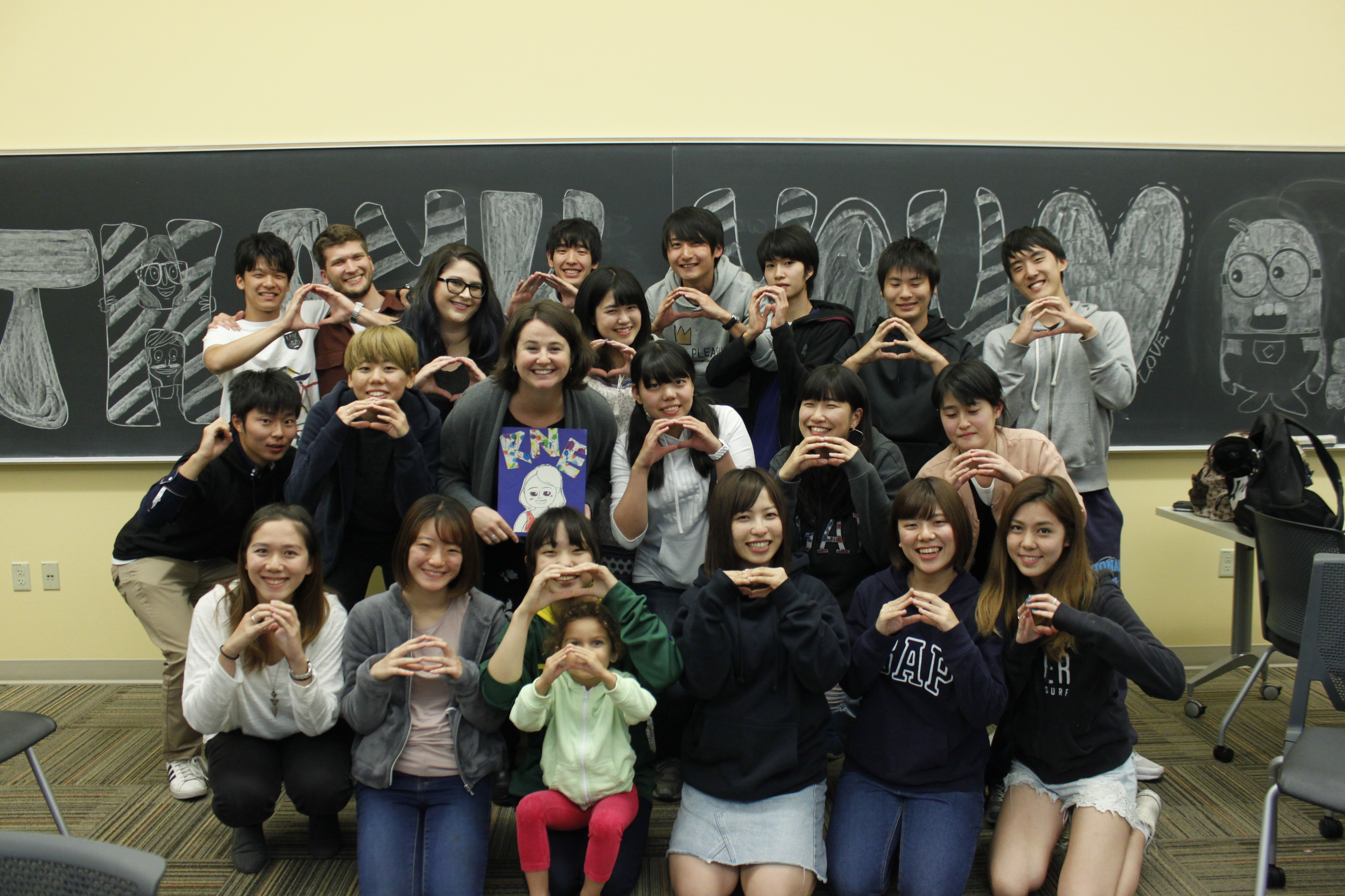 Smiling students standing in classroom in front of black board