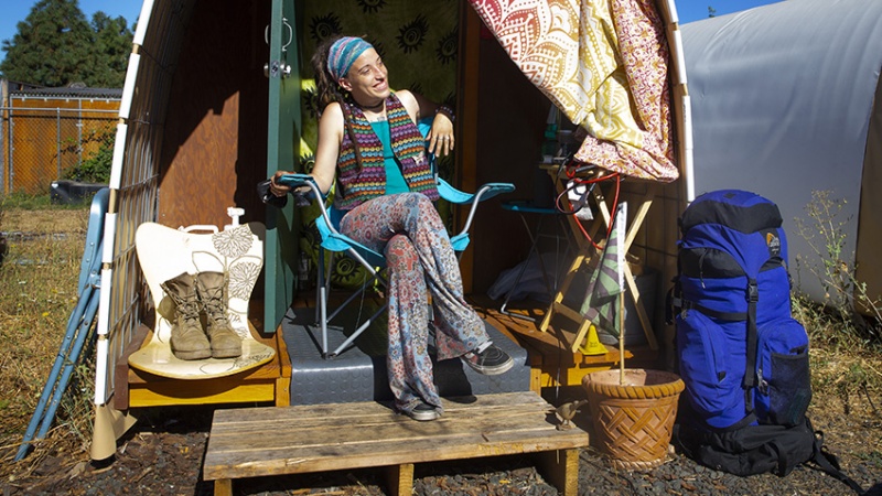 Woman sits on the deck of her tiny home