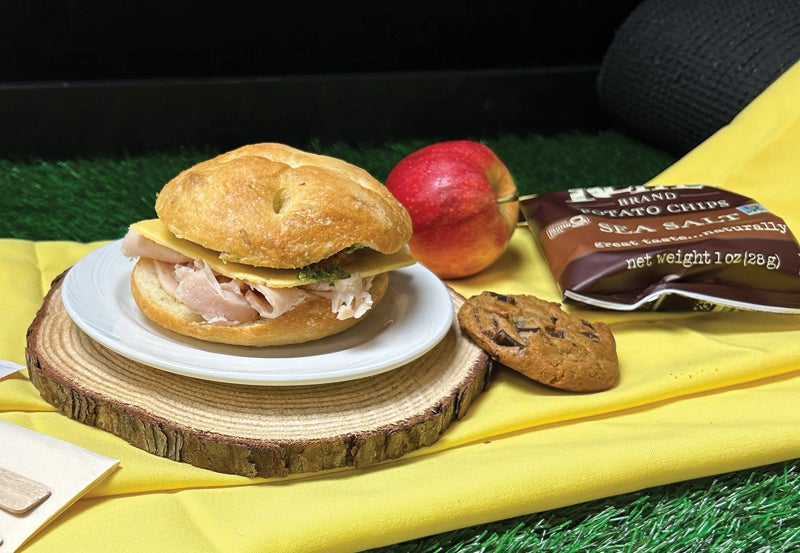 Photo of sandwich, apple, cookie and bagged chips.