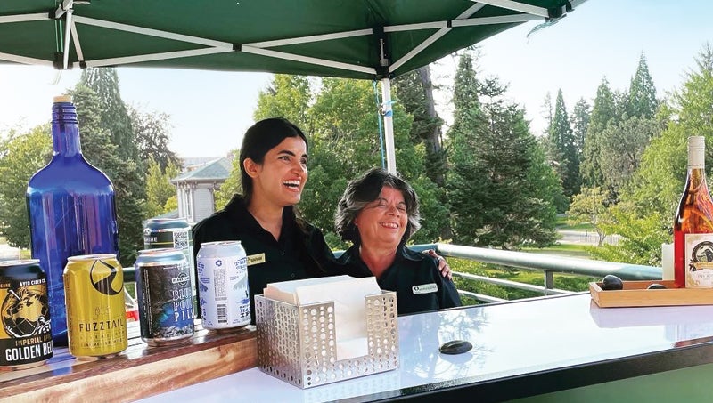 Photo of two catering staff members bartending outdoors.