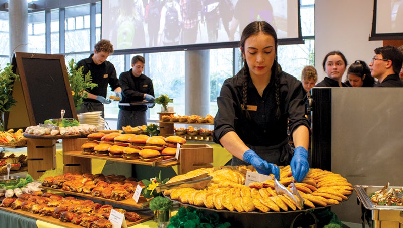 Photo of catering staff putting food on a buffet.