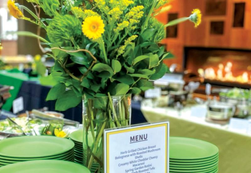 Green plates with flowers with heated trays on table in background.