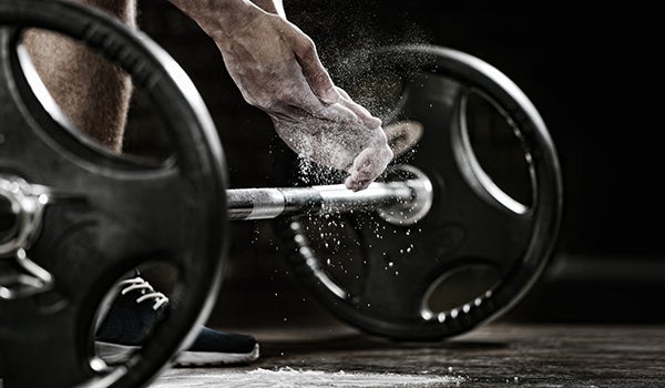 Person with chalk on hands prepares to lift a heavy weight