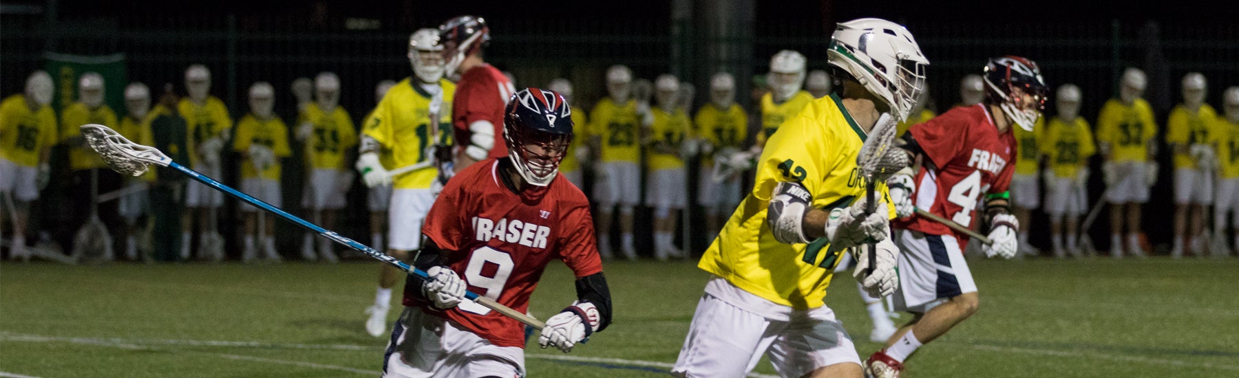 Students playing lacrosse grass field.