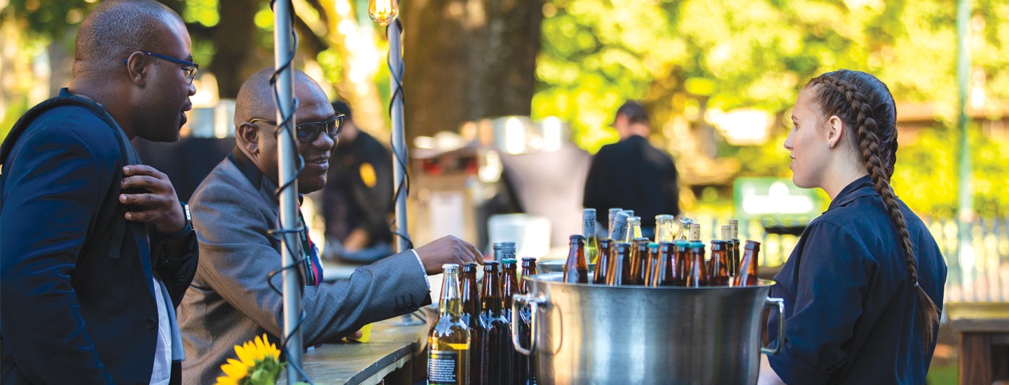 Two adults getting beverages at catered event.