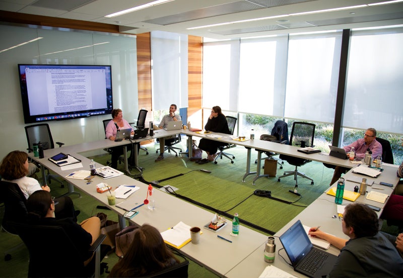 People gathered in a meeting space with document displayed on TV.