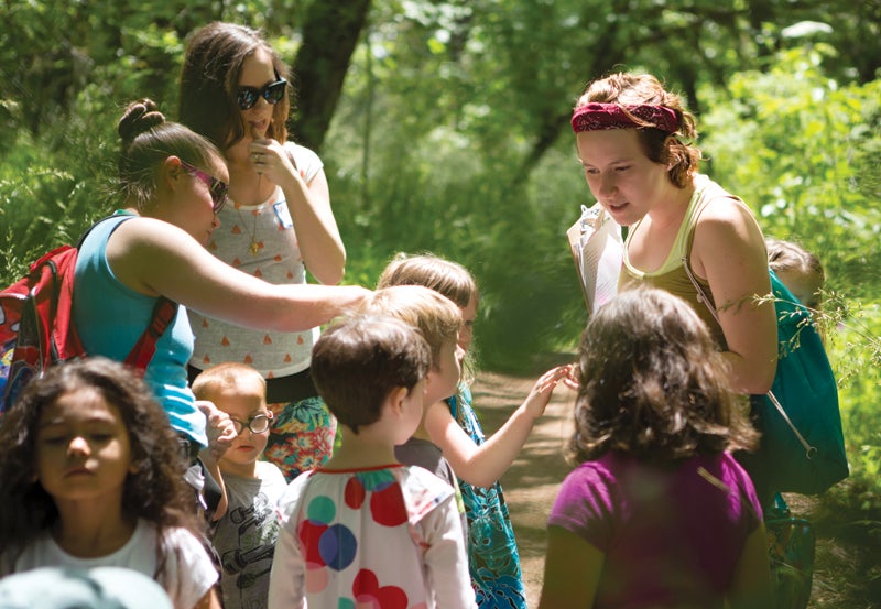 Young adults leading children on nature hike.