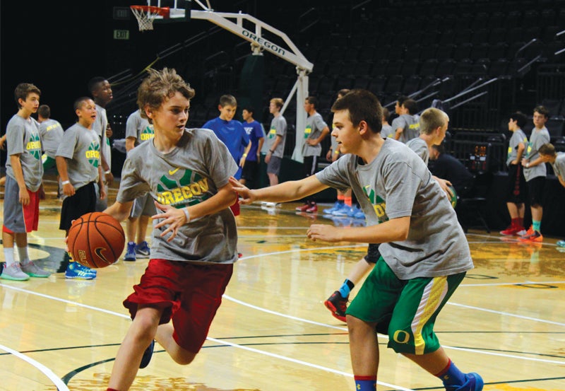 Young adults playing basketball on indoor basketball court.