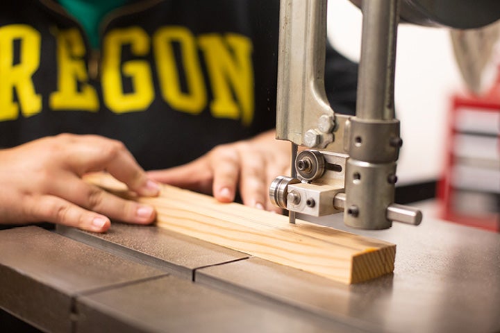 Craft Center member using band saw to cut wood strip.