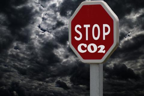 A stock image of a gloomy sky with a stop sign that has "CO2" written below it.