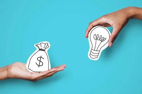 Two hands holding drawings of a lightbulb and a money sack.