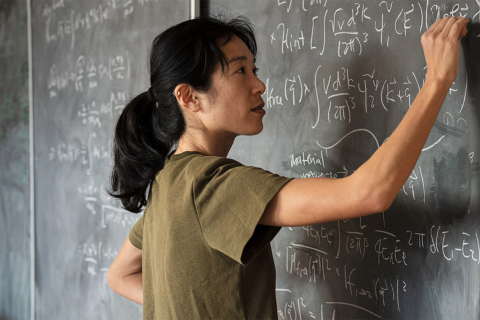 Tien-Tien Yu writing on a blackboard.
