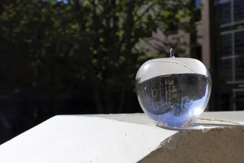 A crystal apple sits on a ledge in the sunshine reflecting Lillis Hall at the University of Oregon.