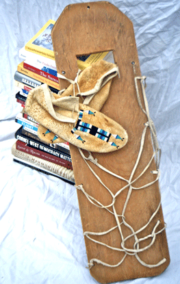 A craddleboard, moccassin, and books