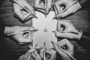 A group of hands writing on a single page.