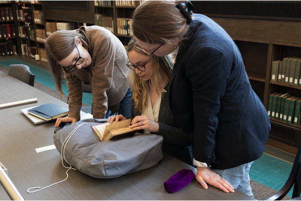 3 CSWS affiliates reading together huddled over a table. 