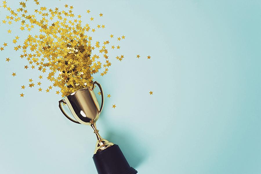 Gold star confetti spilling out of a gold trophy on a light blue background.