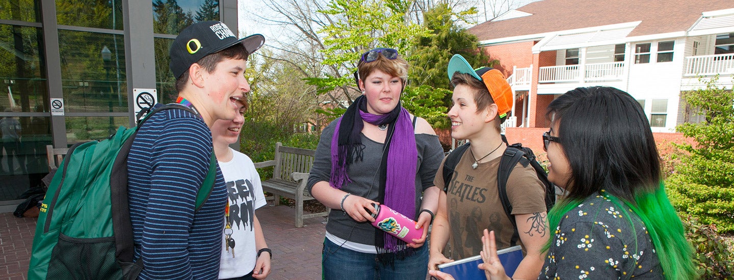 5 students standing in courtyard talking.