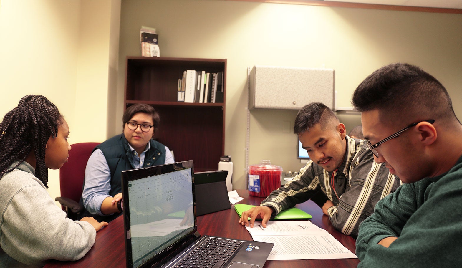 Two student mentoring two other students at a table.