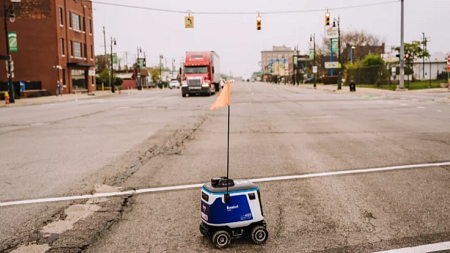 A Kiwibot delivery robot trying to cross Michigan Avenue in Detroit.