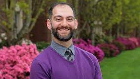 Oregon Law Professor Michael Fakhri smiles in a purple sweater