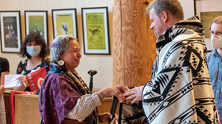 Collaborators shake hands as they meet in the Many Nations Longhouse