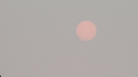 The sun looks dim and orange behind a screen of thick wildfire smoke