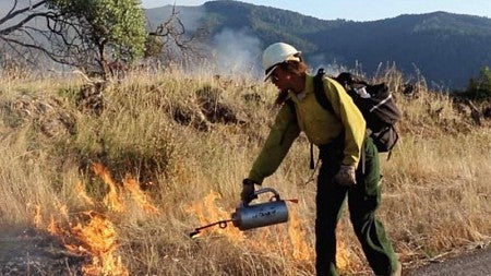 Aja Conrad, the Karuk Tribe’s workforce and internships coordinator, lights a prescribed fire in Orleans, California. Jenny Staats, CC BY-ND