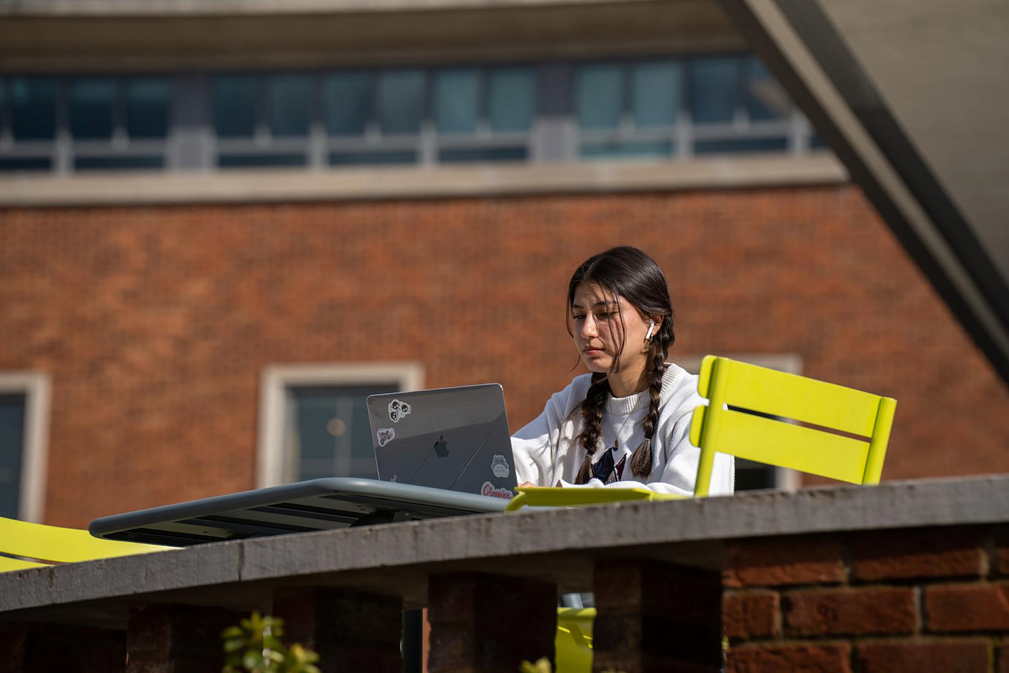 student on a laptop sitting outside the E M U