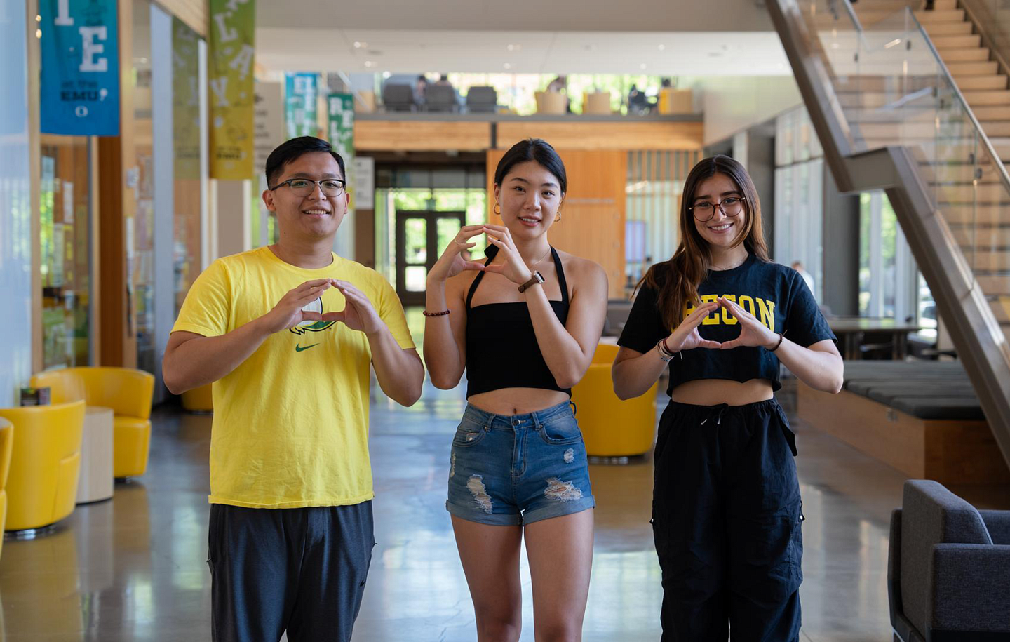 three students making the oregon O with their hands in the E M U