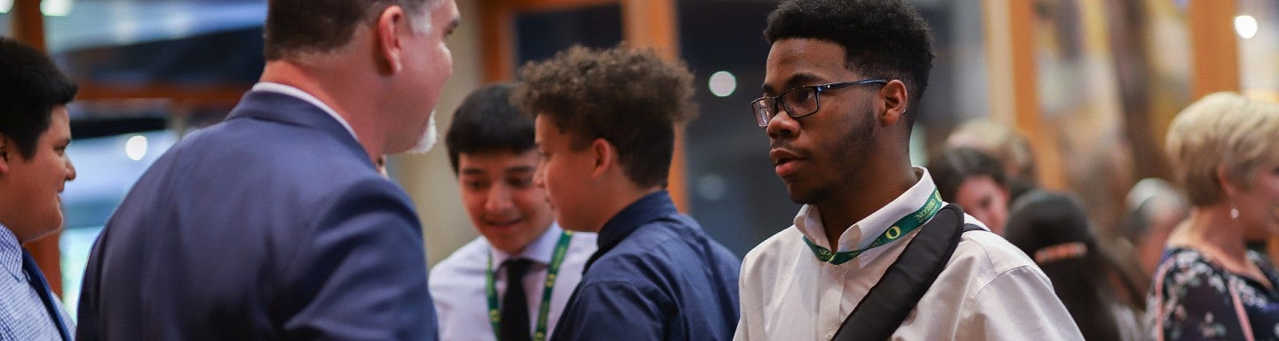 SAIL student talks to man wearing suit.