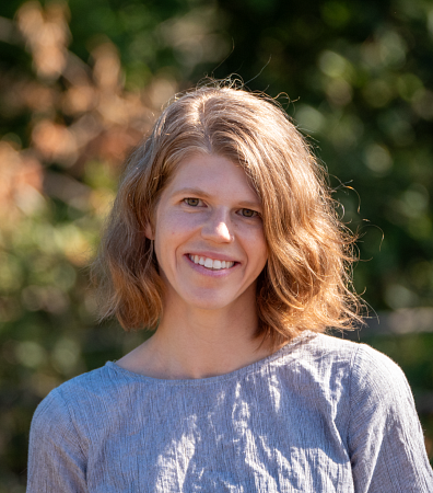 Woman in gray shirt smiling and standing outside