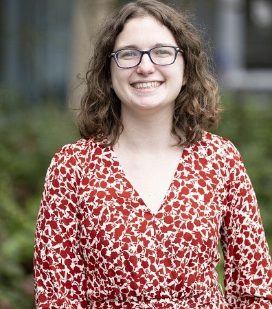 Hope Healey photo wearing red and white print dress and glasses, smiling