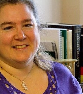 Woman in purple shirt in front of bookshelf